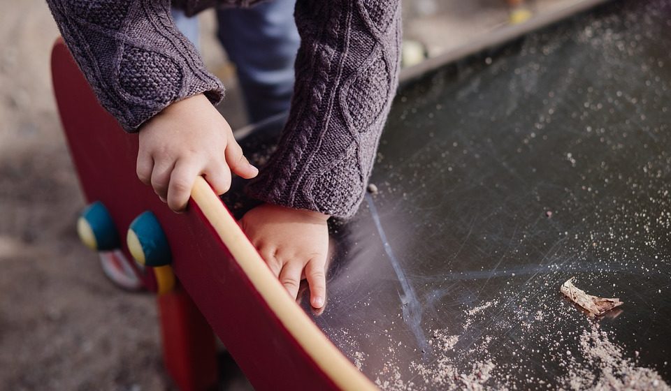 little child in a gray sweater playing.